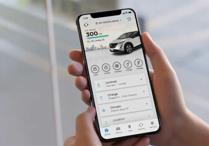 A person holding a phone showing the MyNissan App.